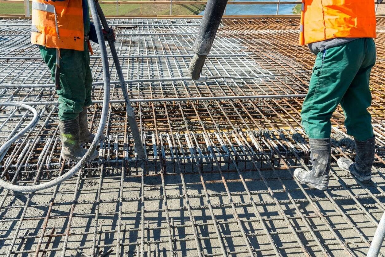 Two workers are using a hose to connect the reinforcement bars.